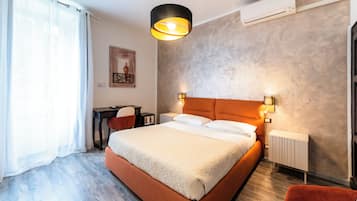A bedroom with a large bed, a desk, a chair, a radiator, and a wall-mounted air conditioner.