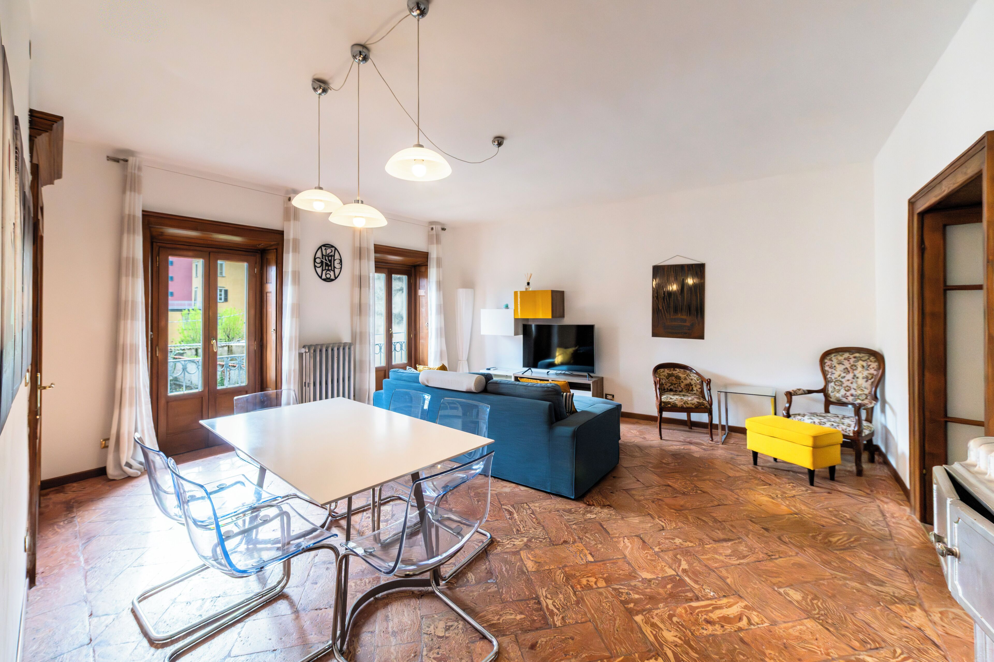Een eethoek met een tafel en stoelen, een bank en een televisie in een woonkamer.
