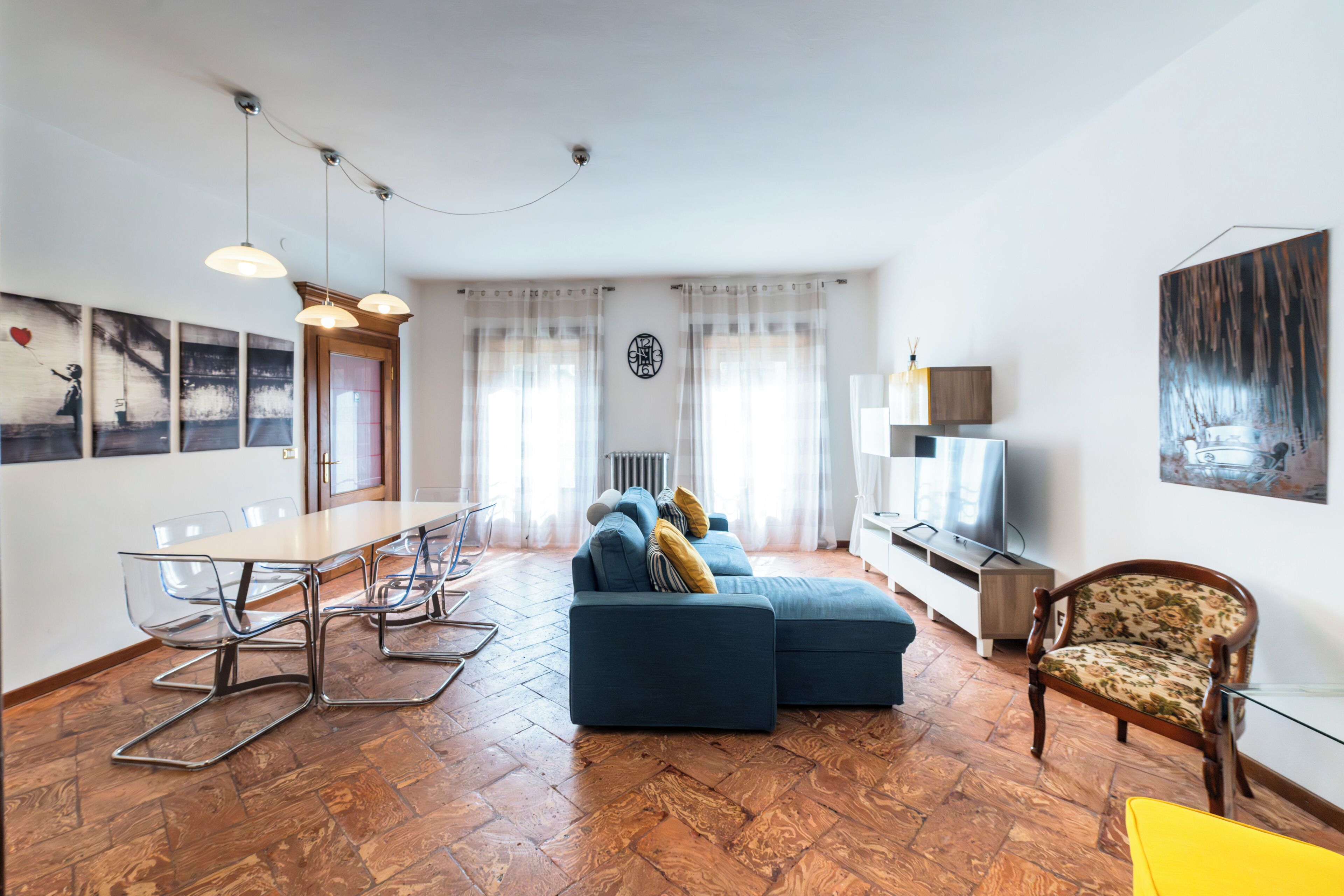 Ein Wohnzimmer mit einer Couch, einem Esstisch mit Stühlen, einem Fernseher und einem Sessel.