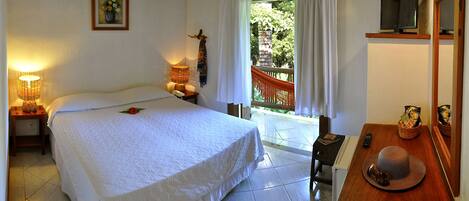 A bedroom with a bed, a nightstand with a lamp, a TV, and a window with curtains.