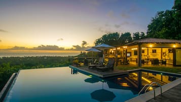 Una piscina al aire libre, sombrillas, sillones reclinables de piscina