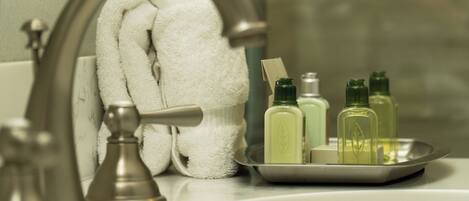 A bathroom sink with a towel hanging on a towel rack, a soap dish with bottles, and a faucet.