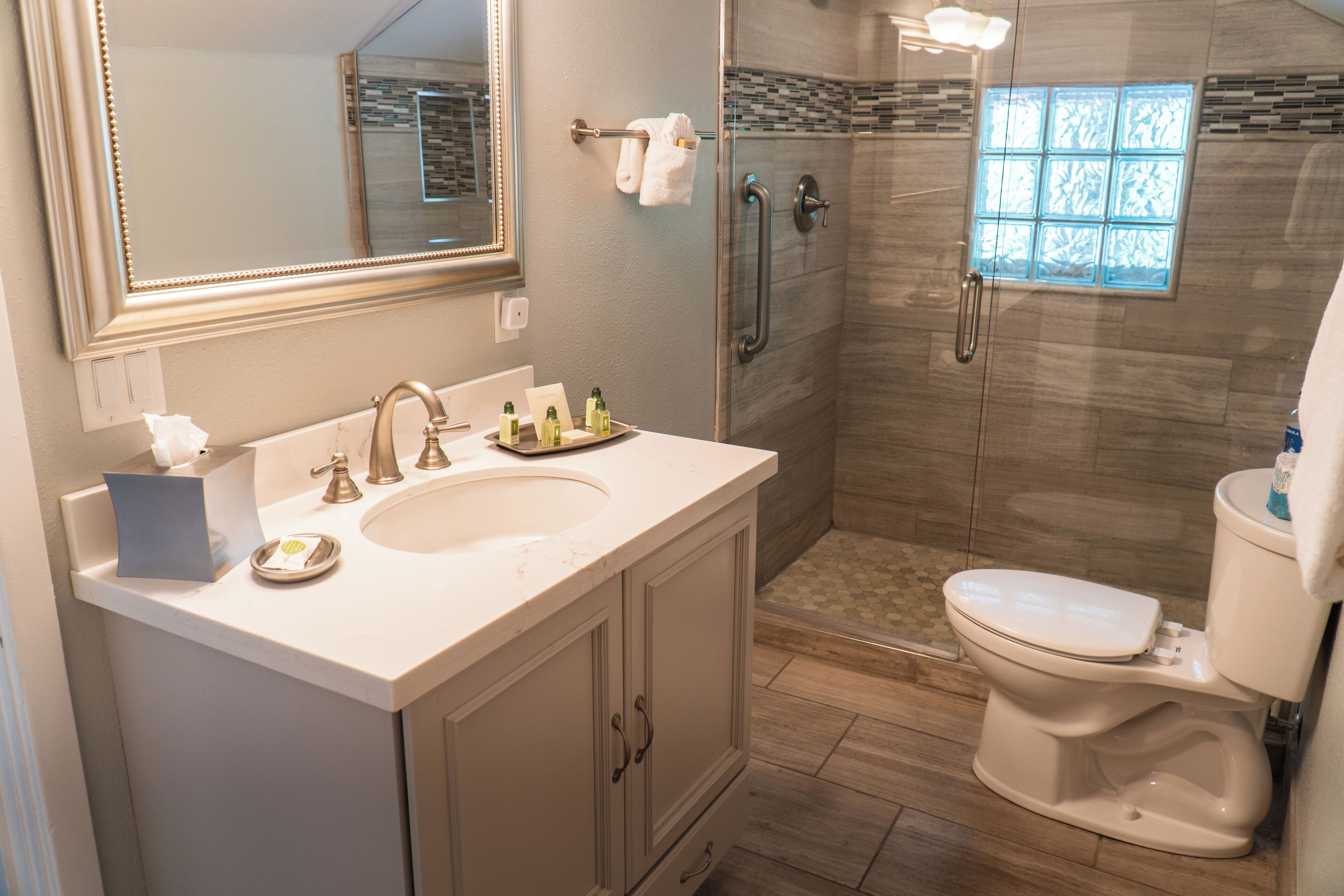 Un baño moderno con un espejo grande, un lavabo, un inodoro y una zona de ducha.