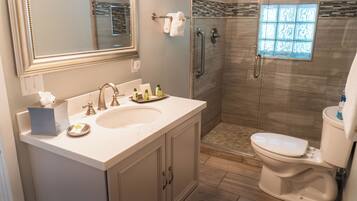 Un baño moderno con un espejo grande, un lavabo, un inodoro y una zona de ducha.