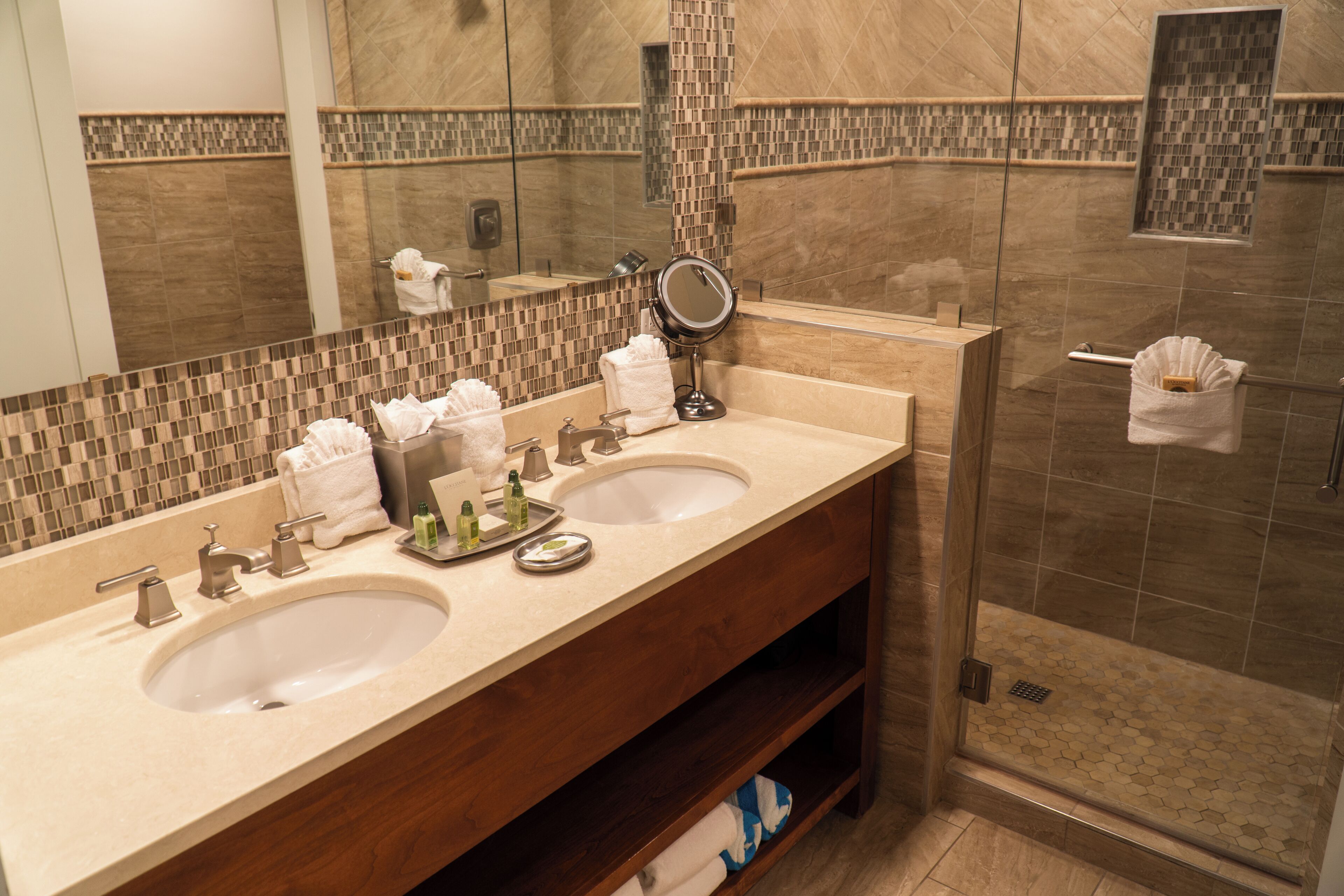 A bathroom with two sinks, a mirror, and a shower area.
