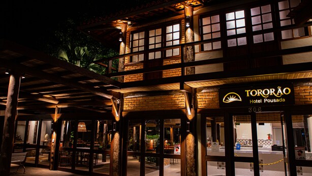 The exterior of Hotel Tororão with a wooden facade, large windows, and a signboard. - Pousada Tororão (Porto Seguro)