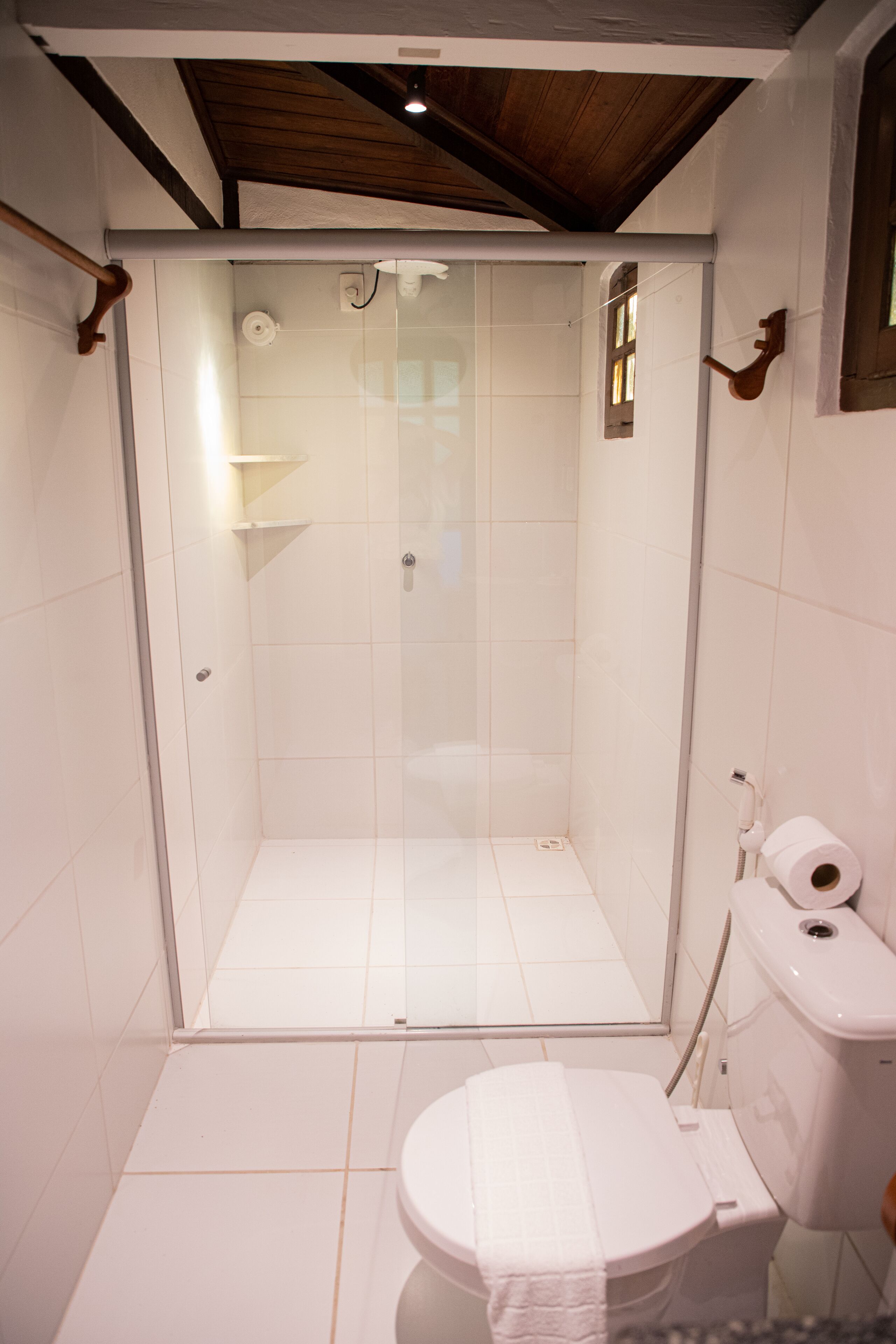 A bathroom with a glass-enclosed shower, a toilet, and a sink.