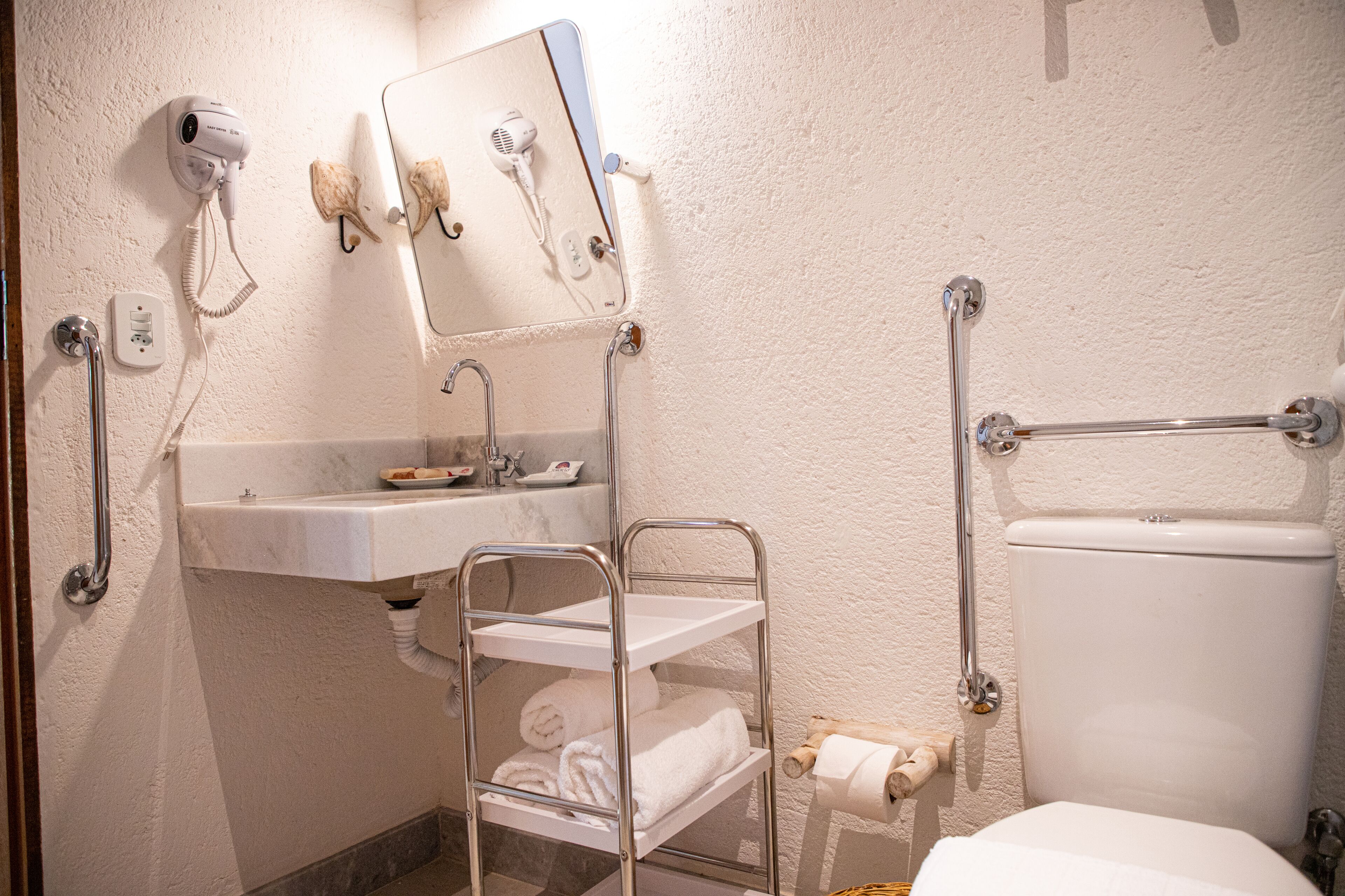 A bathroom with a white sink, a mirror, a towel rack, a toilet, and a shower head.
