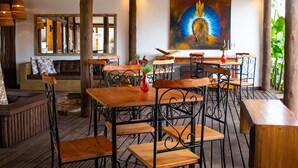 A wooden deck with tables and chairs, a sofa, and a painting on the wall. - Pousada Tororão (Porto Seguro)