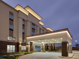 Una entrada de hotel moderna con un cartel de 'Welcome', señalización clara y una fachada bien iluminada.