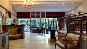 A spacious hotel lobby with a wooden reception desk, a chandelier, and a large window offering a view of the outdoors. - Villa Blanche Hotel (Istanbul)