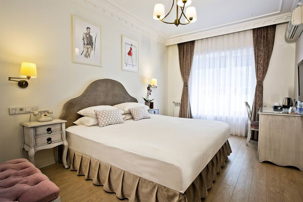 A neatly arranged hotel room with a large bed, bedside lamps, a desk, and a chair.