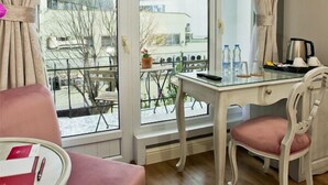A room with a large window, a table with a pink tablecloth, a white chair, and a small balcony area with a table and chairs. - Villa Blanche Hotel (Istanbul)