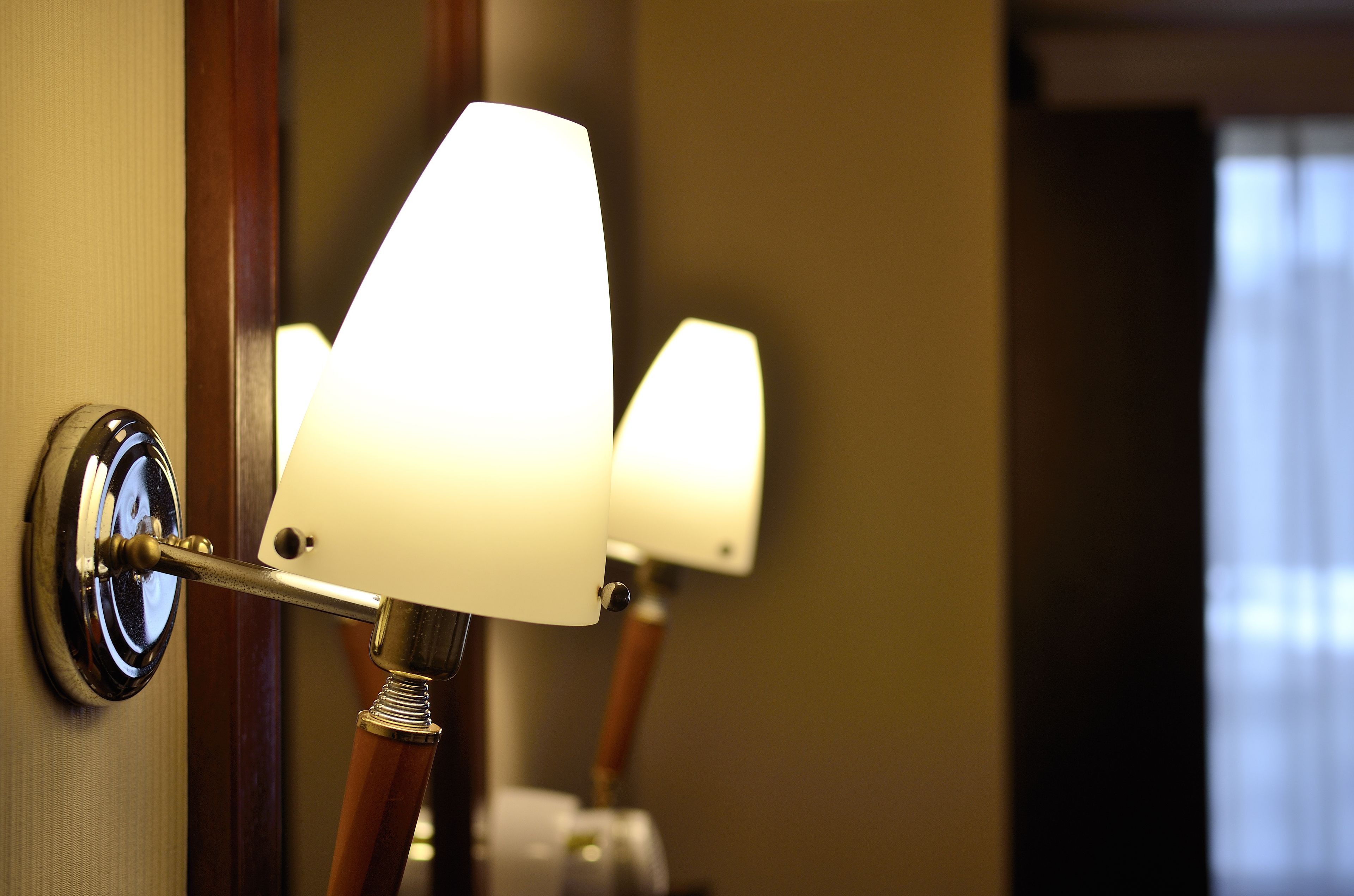 A close-up of a wall-mounted lamp with a white shade and a wooden base.