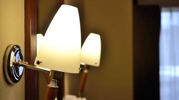 A close-up of a wall-mounted lamp with a white shade and a wooden base.