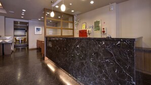 A reception area with a marble counter, seating area, and a staircase leading to an upper level. - Goodness Hotel (Kaohsiung)