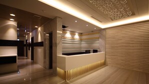 A modern reception area with a marble counter, recessed lighting, and a wooden panel wall. - Leesing Hotel (Kaohsiung)