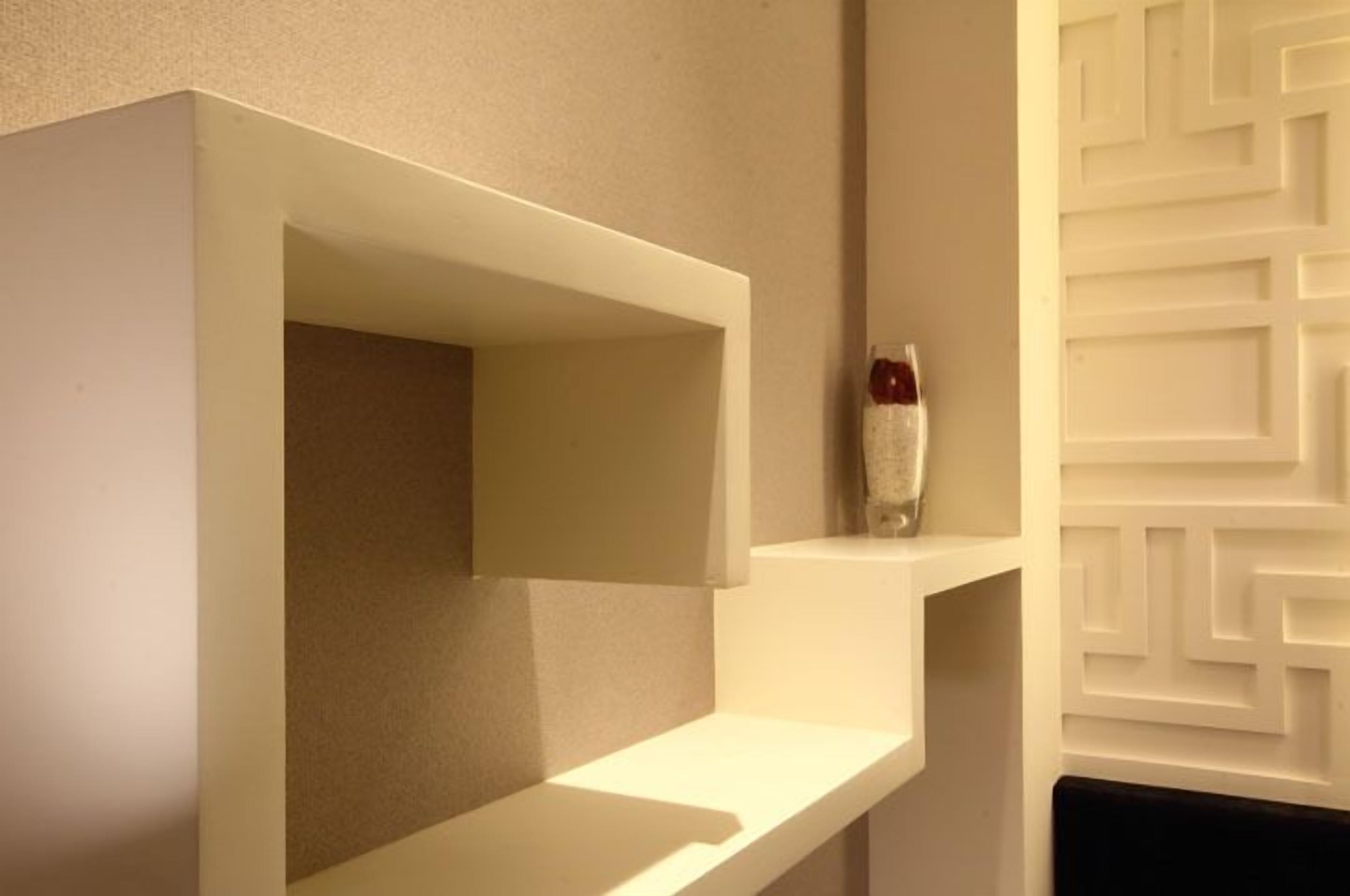 A modern bathroom with white fixtures and a geometric wall design.