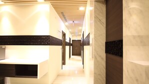 A modern hotel lobby with a long corridor, a reception desk, and a marble wall. - Leesing Hotel (Kaohsiung)