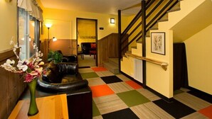 A hotel lobby with a checkered floor, a staircase, a sofa, and a vase of flowers. - Moderne Hostel (Mammoth Lakes)