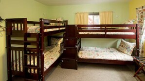 A bunk bed room with two wooden bunk beds, a window with curtains, and a carpeted floor. - Moderne Hostel (Mammoth Lakes)