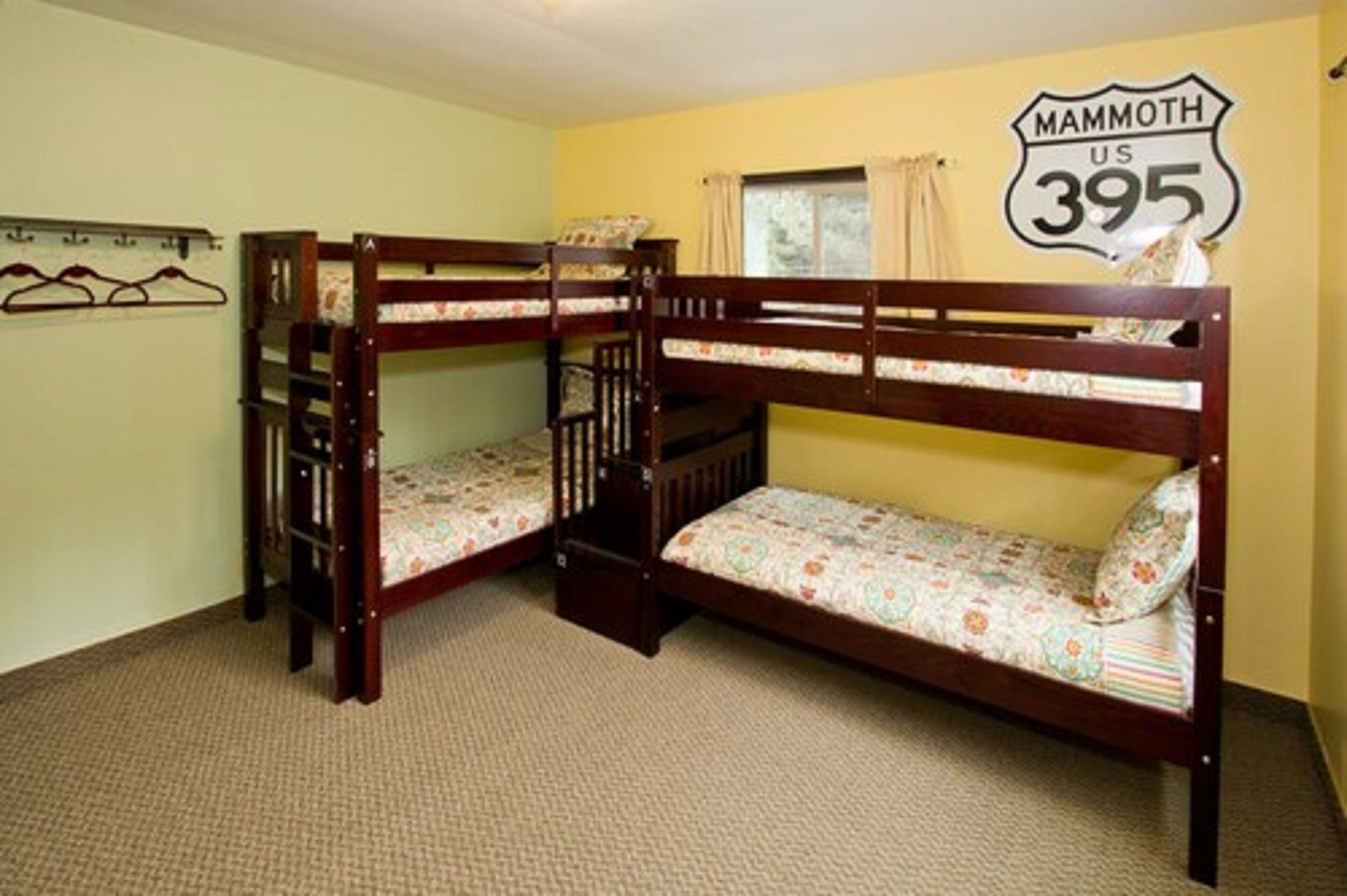 A room with two bunk beds, a wall-mounted coat rack, and a sign reading "Mammoth US 395".