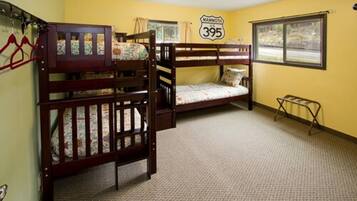 A bunk bed room with a 'Mammoth US 395' sign on the wall, carpeted floor, and a window with curtains.