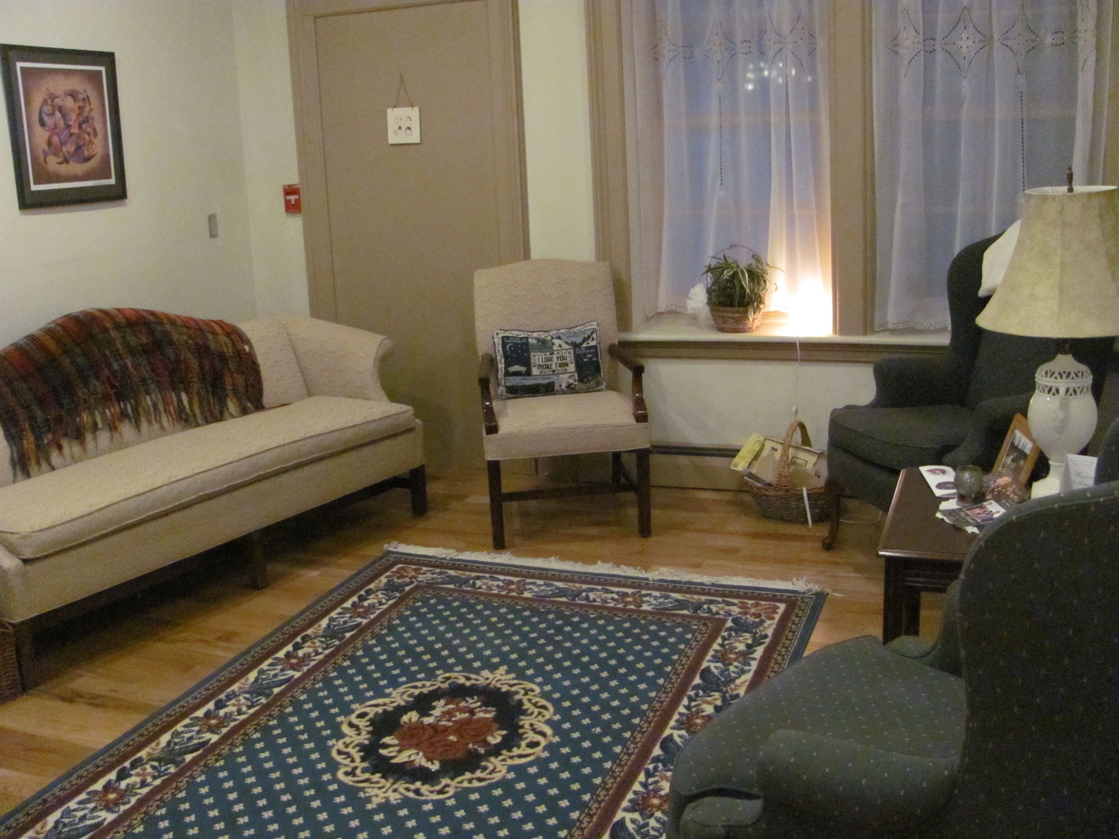 A living room with a sofa, armchair, and a patterned rug.