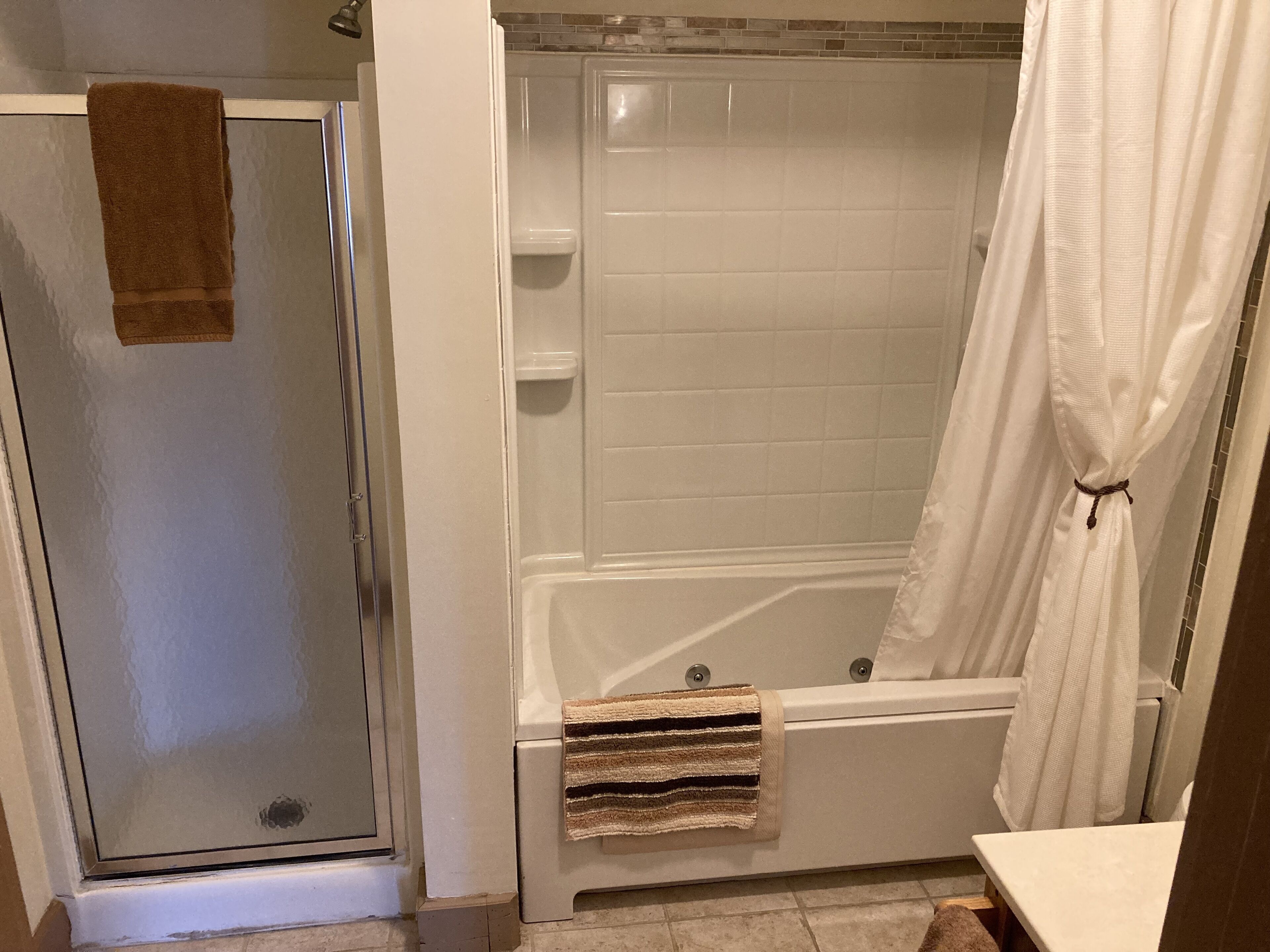 Un baño con cabina de ducha de vidrio, bañera y retrete.
