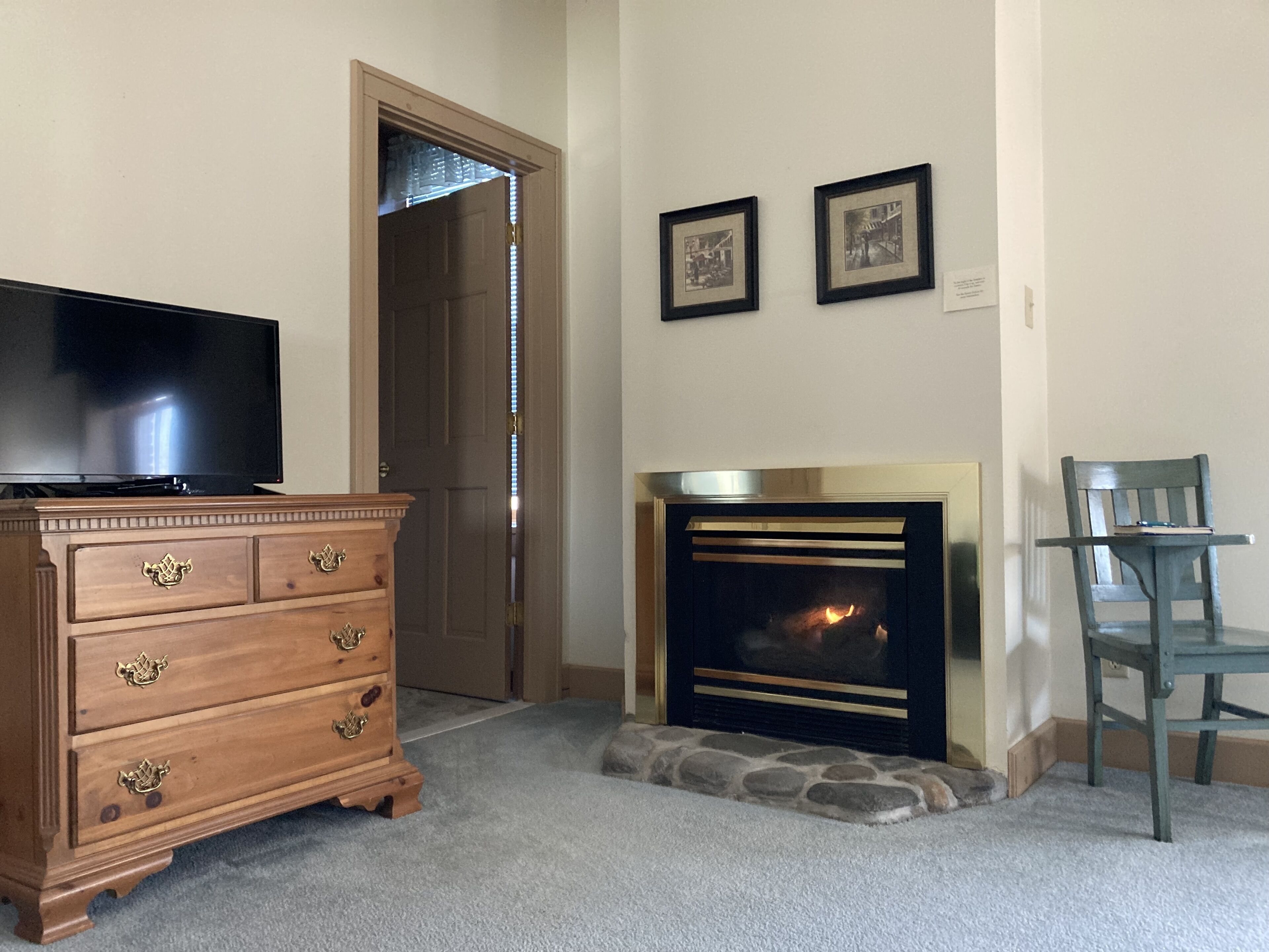 Una habitación con un aparador de madera, un televisor, una chimenea y dos cuadros en la pared.