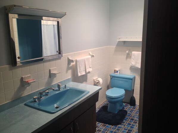 Une salle de bain avec un lavabo bleu, des toilettes et un sol carrelé de carreaux bleus.
