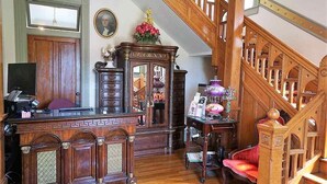 A traditional interior with a wooden staircase, a desk with a computer, and a red chair. - 1895 Washington Hotel (Paducah)