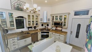 A kitchen with white cabinets, granite countertops, a stainless steel sink, a stove, and a microwave. - 1895 Washington Hotel (Paducah)