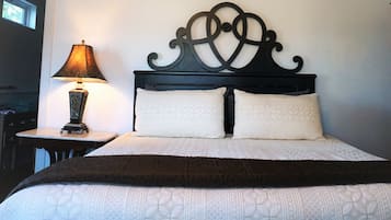 Una cama bien hecha con un cabecero decorativo, una lámpara de noche y una mesita con lámpara.