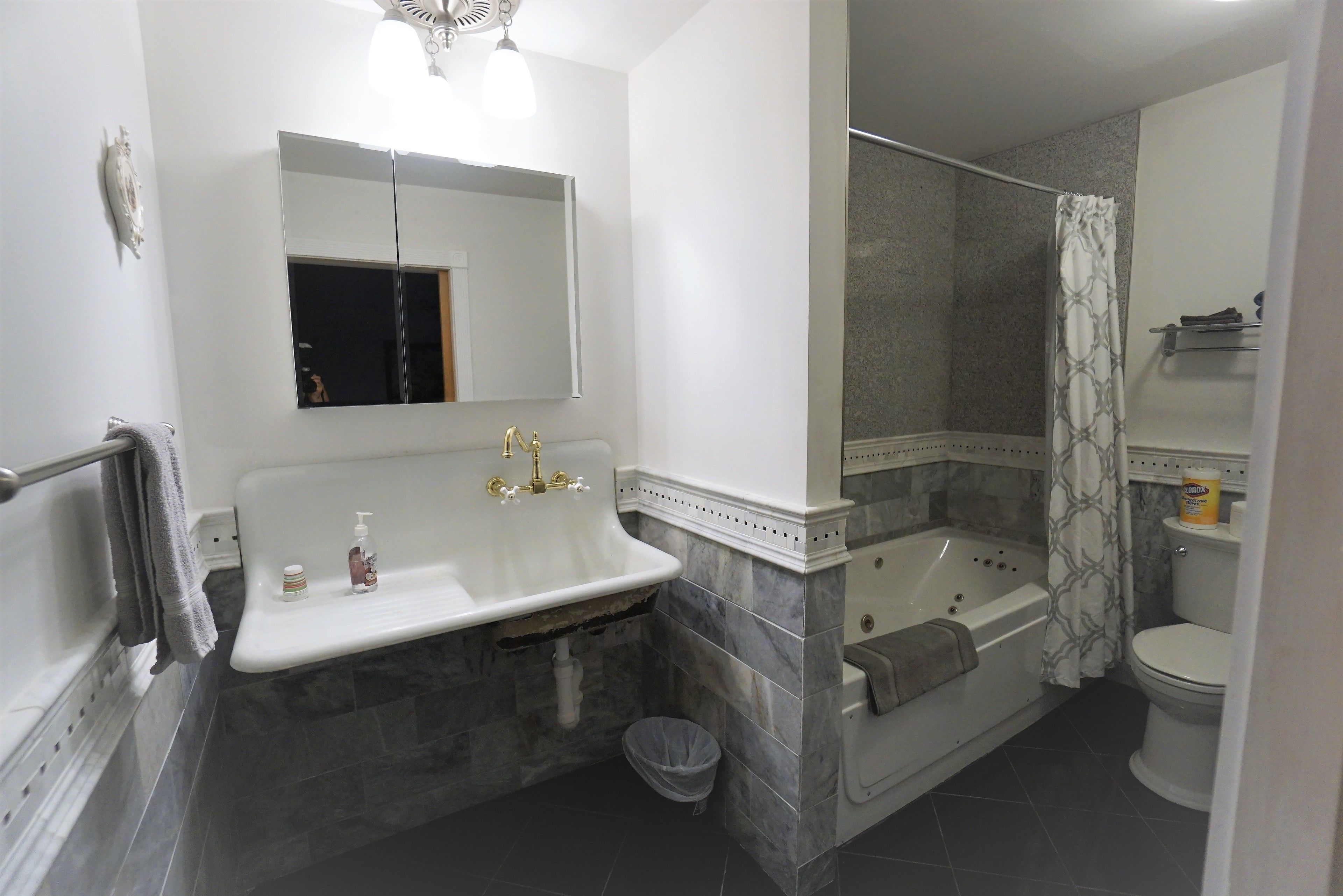 Een badkamer met een wit wastafelmeubel, een spiegel, een bad en een toilet.