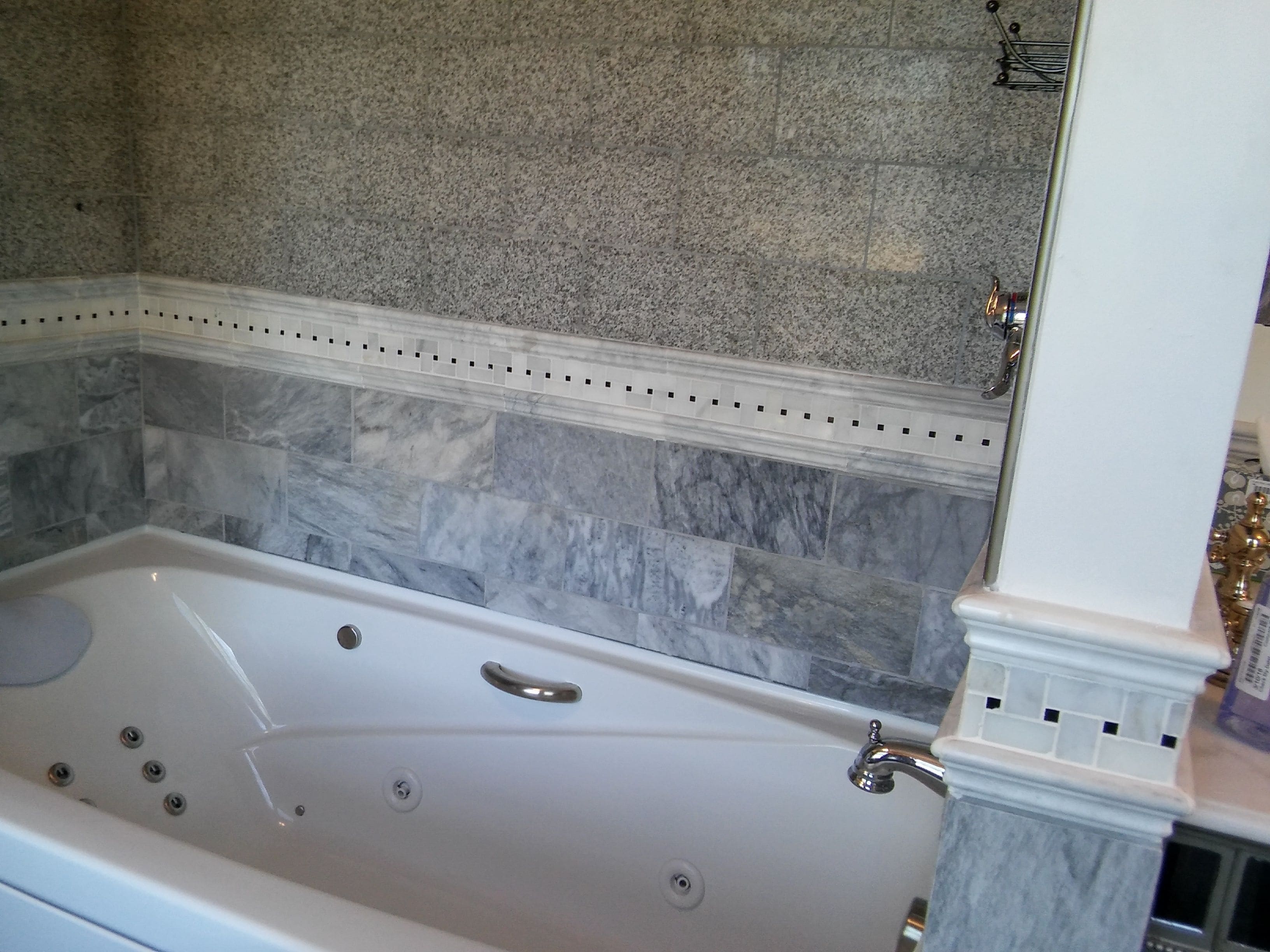 A bathroom with a freestanding bathtub, marble tiles, and a mirror with a gold frame.