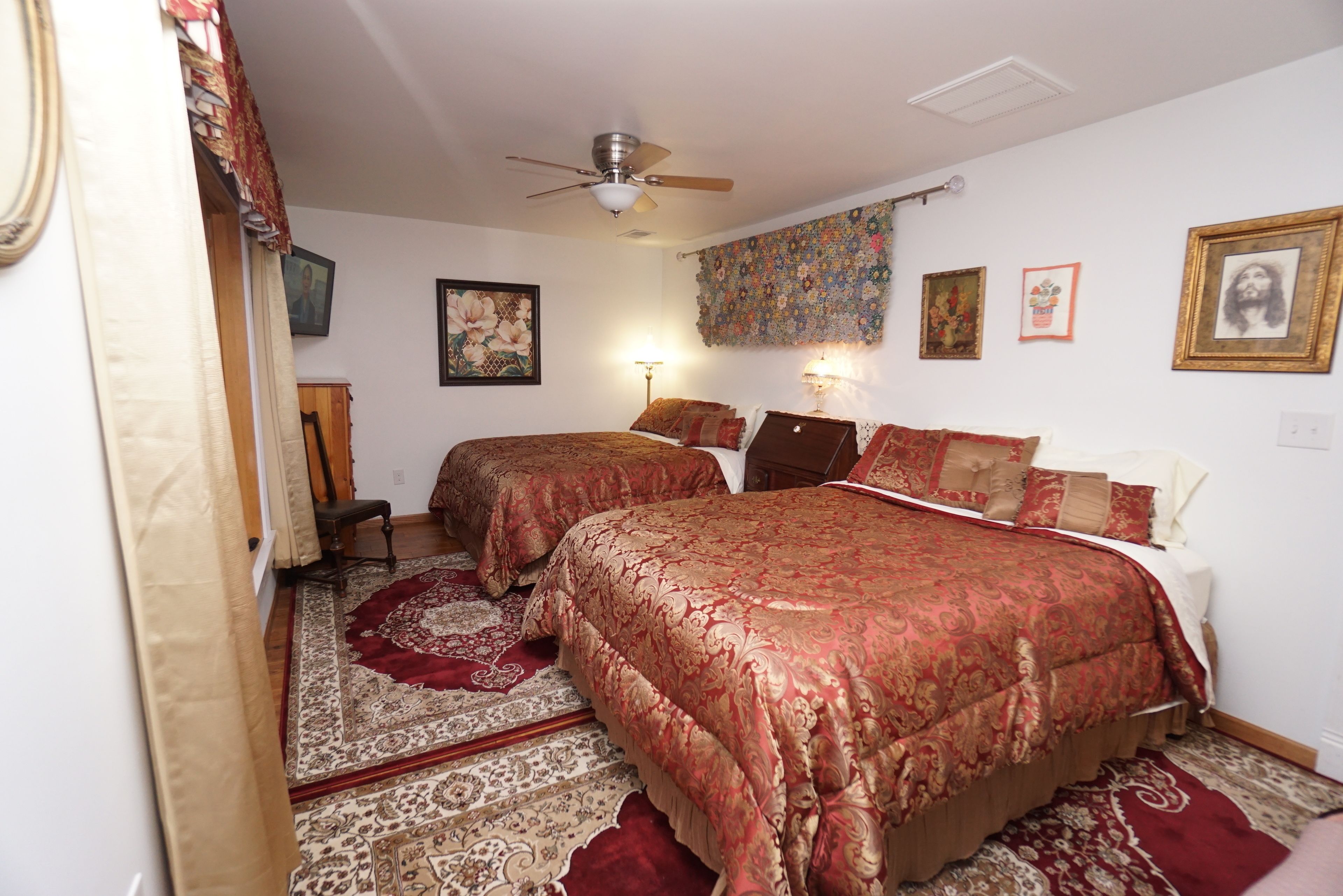 Une chambre avec deux lits, un ventilateur de plafond et un tapis à motifs.