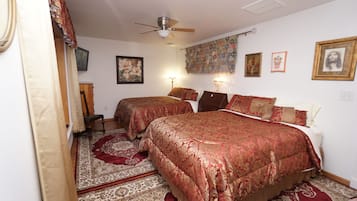 Une chambre avec deux lits, un ventilateur de plafond et un tapis à motifs.