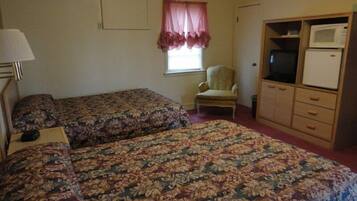 A room with two beds, a chair, a television, and a microwave.