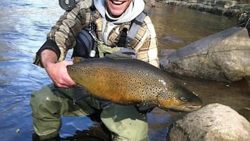 A person holding a large fish in a river.