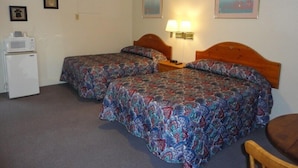 Une chambre d’hôtel avec deux lits, un petit réfrigérateur, une lampe et une chaise.
