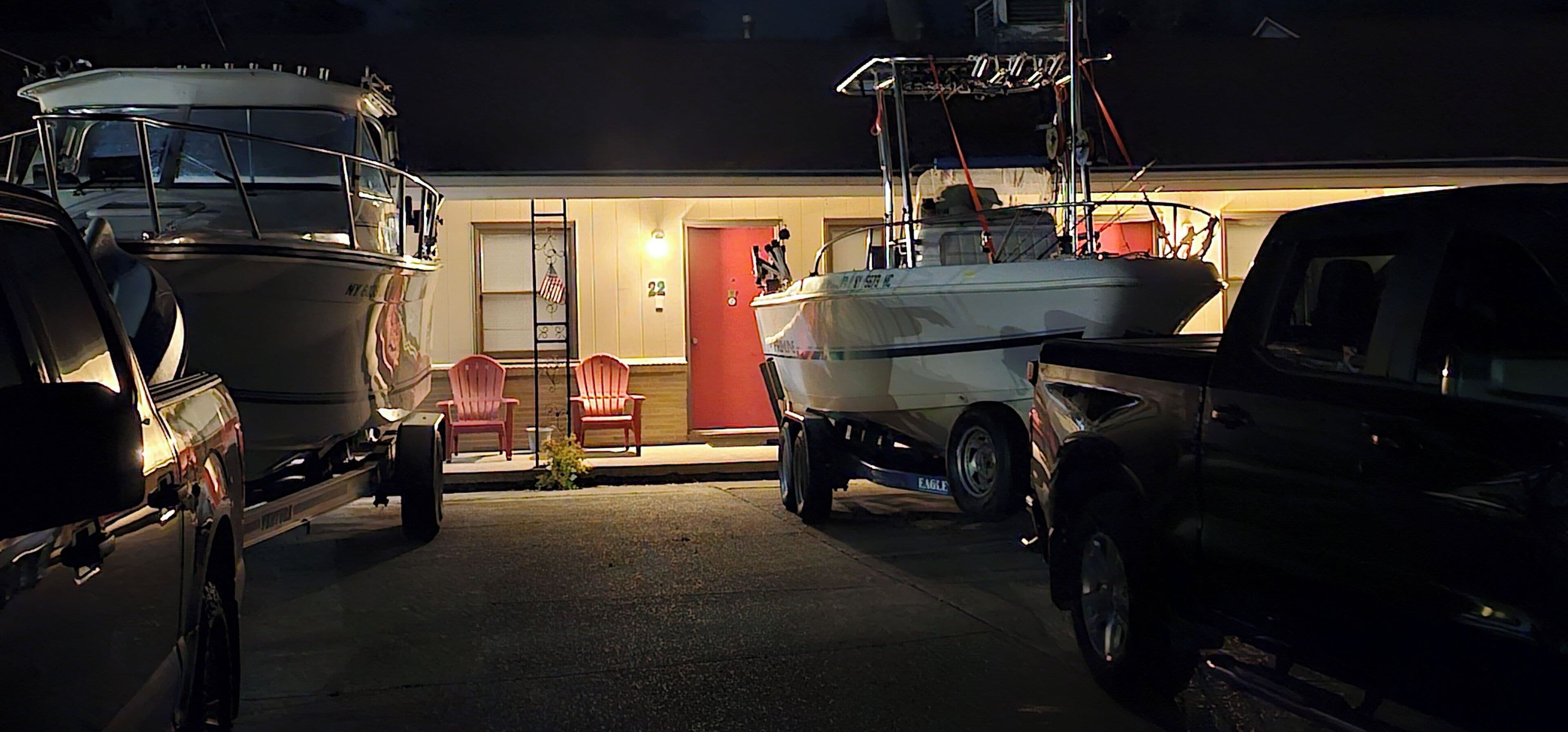 A garage with two boats, a truck, and a red door.