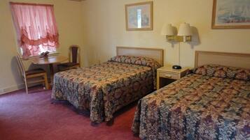 A hotel room with two single beds, a desk with a chair, a small table, and two wall lamps.