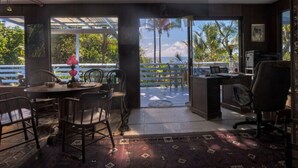 A room with a dining area, a desk, and a view of the outdoors. - Ma'ukele Lodge (Pahoa)