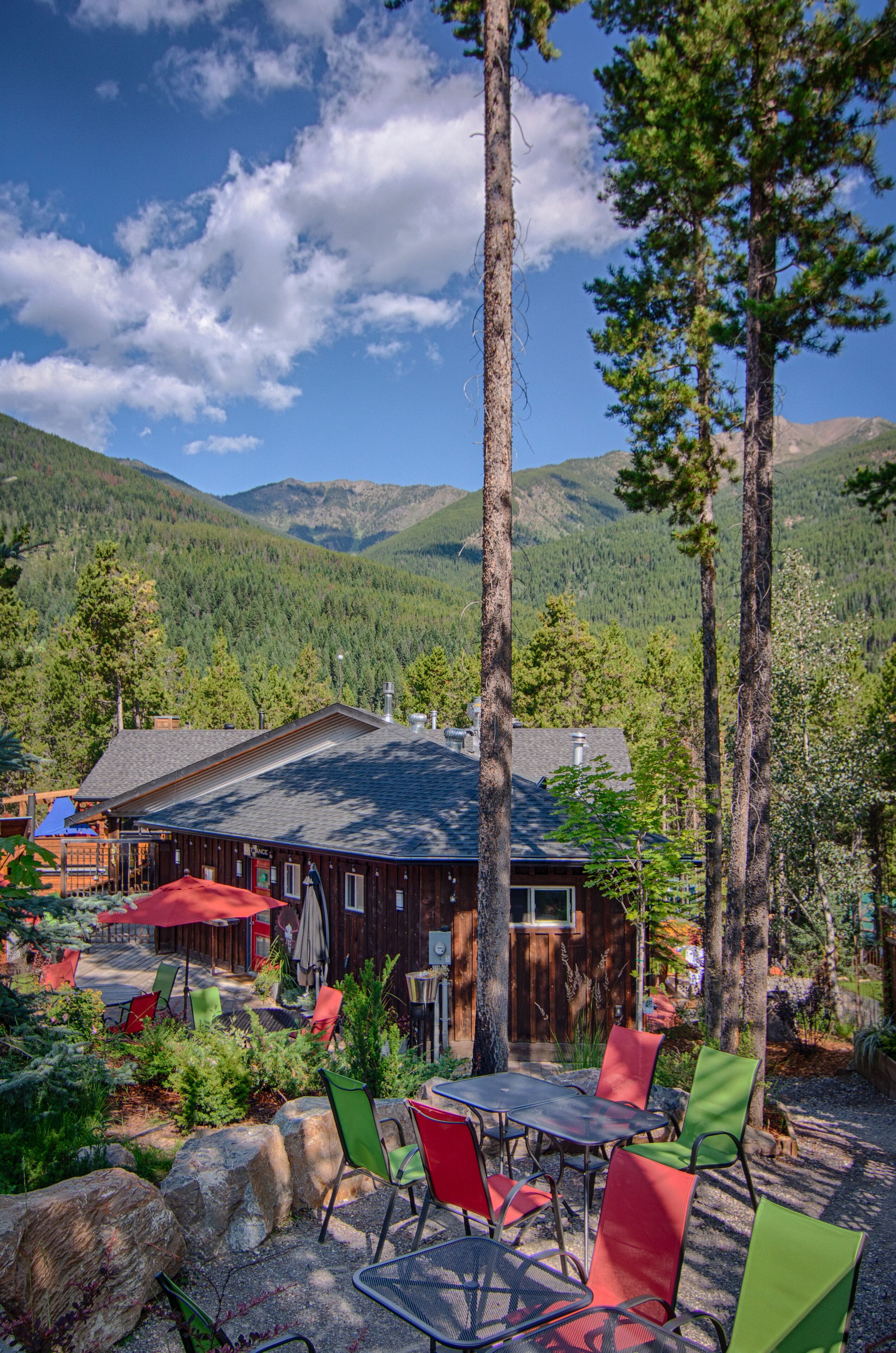 A rustic cabin with a patio area featuring outdoor seating and a mountain backdrop.