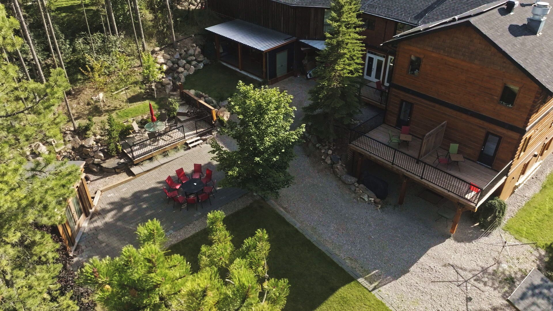 A lodge with a patio area, a covered outdoor seating area, and a large wooden building with a balcony.
