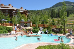 A pool area with a water slide, lounge chairs, and a mountain backdrop.