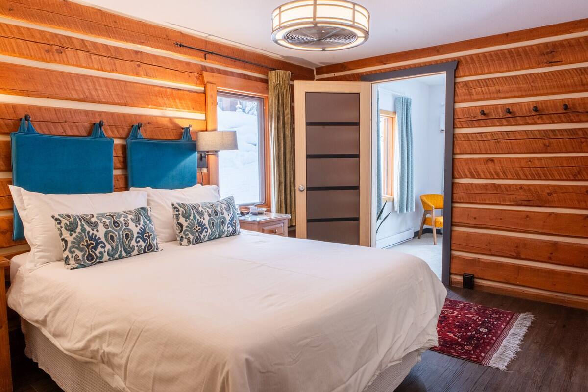 Un dormitorio con una cama grande, paredes de madera, una mesita y una silla.