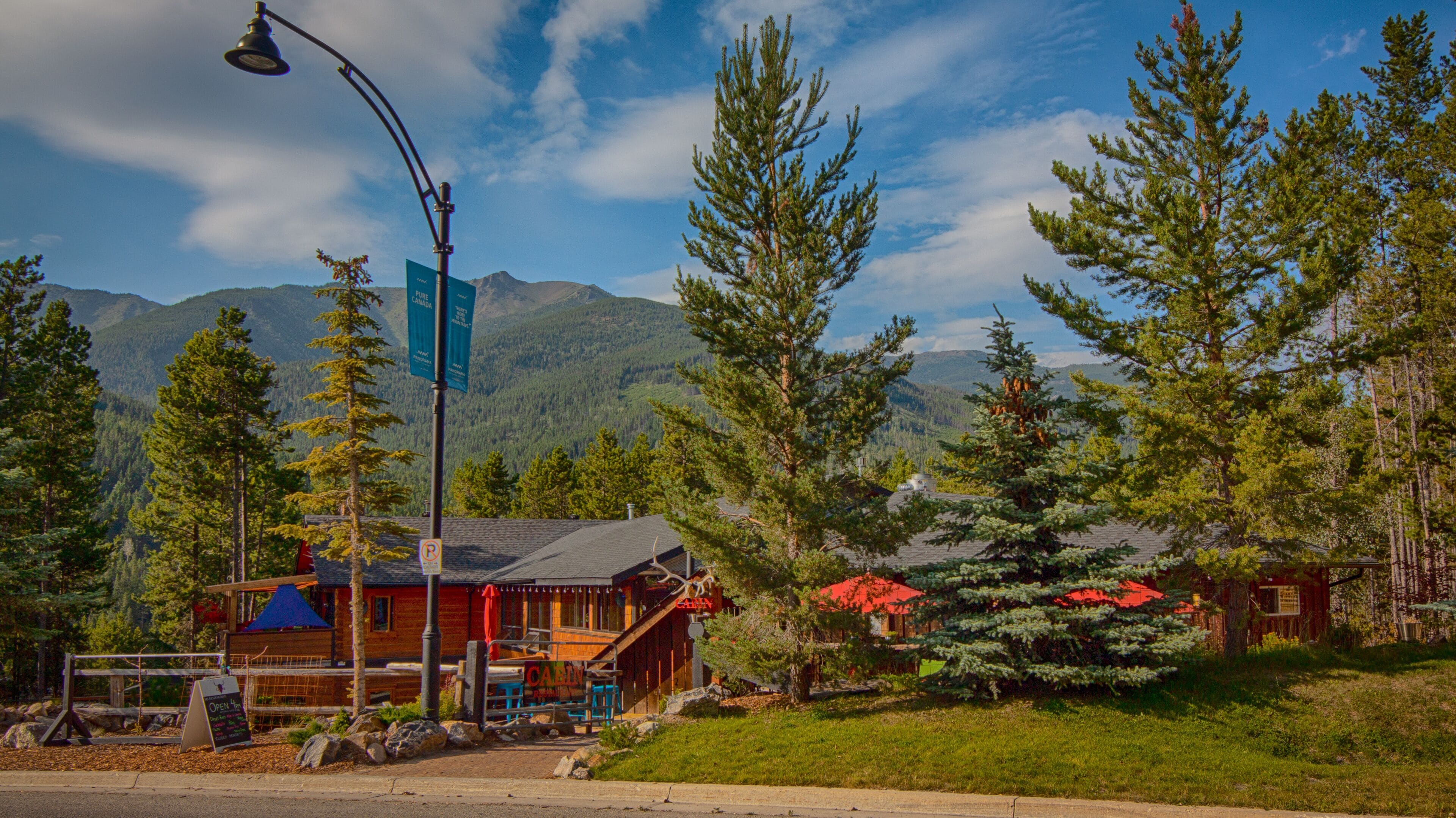 A lodge with a wooden exterior, a covered porch, and a mountain backdrop.
