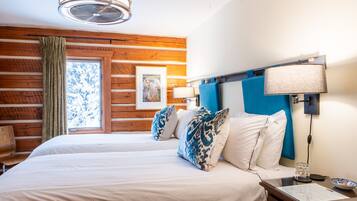 A hotel room with a wooden wall, a bed with white and blue patterned pillows, a nightstand with a lamp, and a framed picture on the wall.